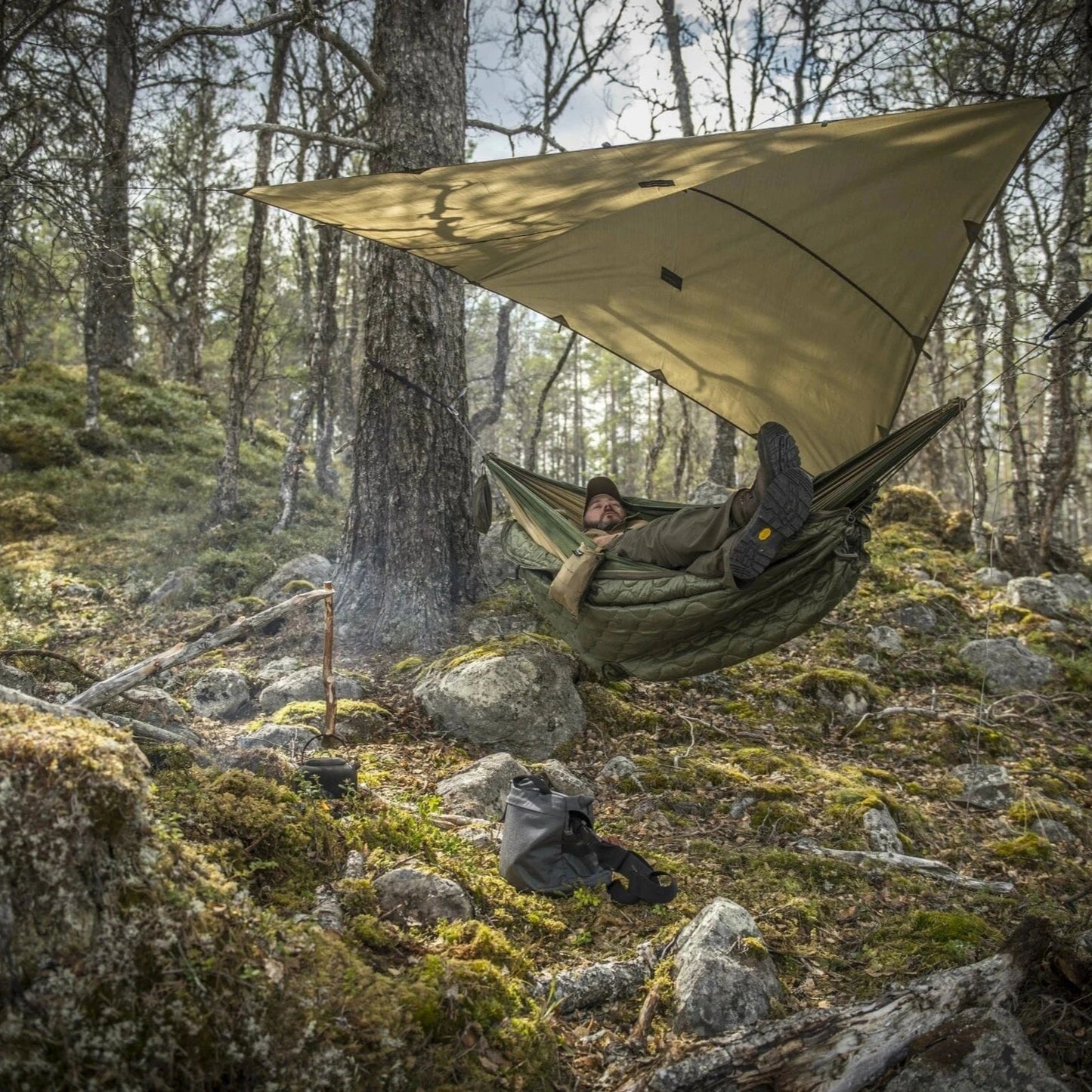 Tarp shelter set up in front of jungle waterfall for bushcraft camping