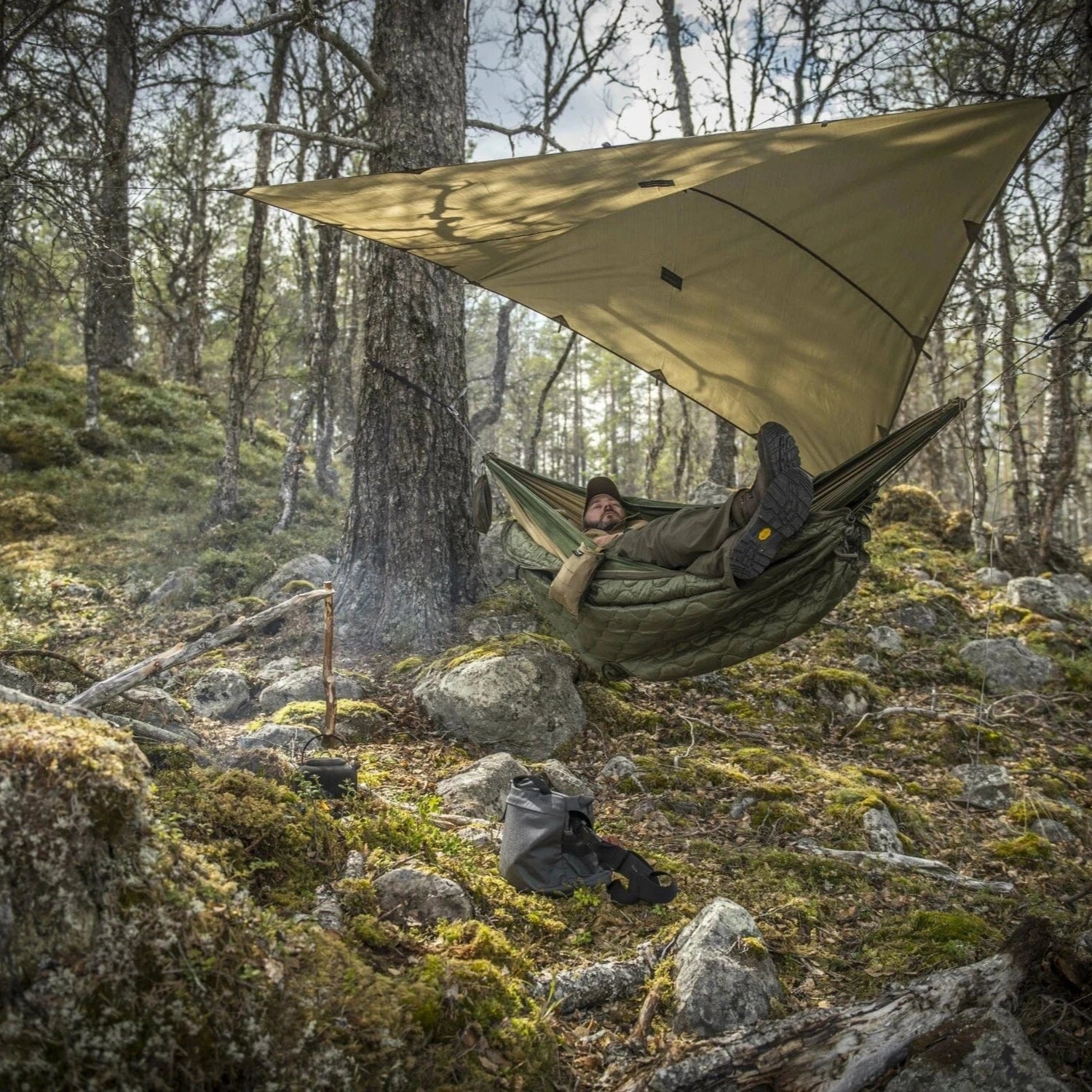Tarp shelter set up in front of jungle waterfall for bushcraft camping