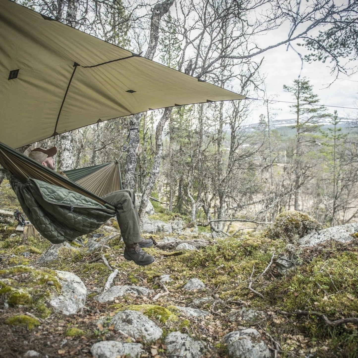Tactical tarp used as lean-to shelter in dense woodland